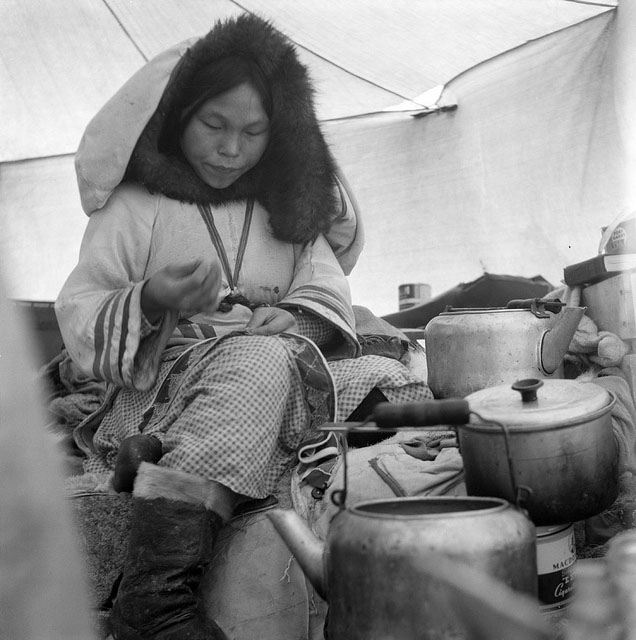 Inuit woman sewing in a tent. 