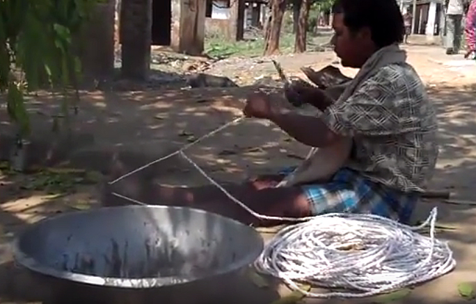 A Birhor man making a rope