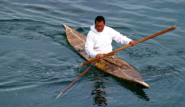 An Inuit hunter in a traditional kayak and carrying a harpoon 