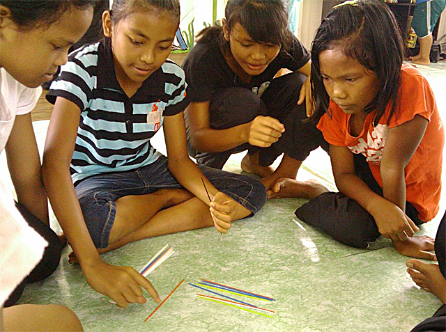 Jakun teenagers playing pick-up sticks in a community center 