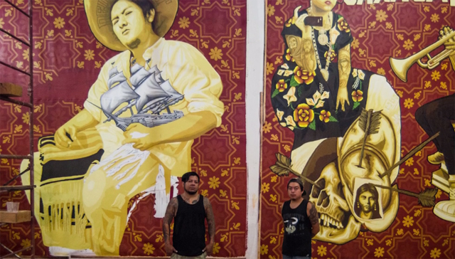 The Zapotec artists Dario Canul and Cosijoesa Cernas standing in front of their murals 