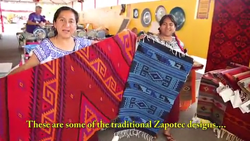 Pastora Gutierrez Reyes (left) and her sister Silvia hold up a couple of their rugs to show off the traditional Zapotec designs 