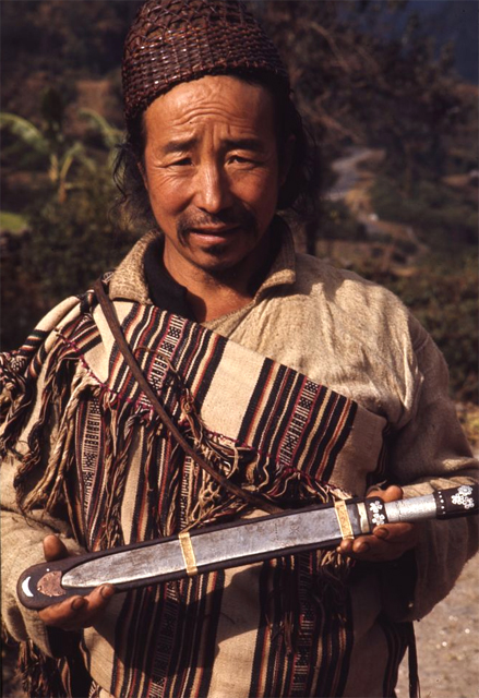 Lepcha man in traditional bamboo hat and woven clothing holding knife in Singhik, Sikkim 