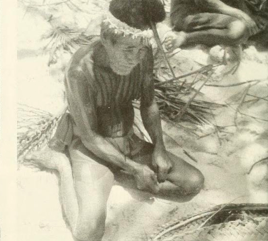 A tattooed man on Fais, a neighboring island to Ifaluk, making sennet, a type of rope
